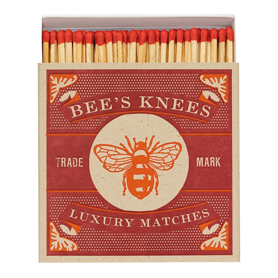 A deep red matchbox reading Bee's Knees Luxury Matches around a bee emblem