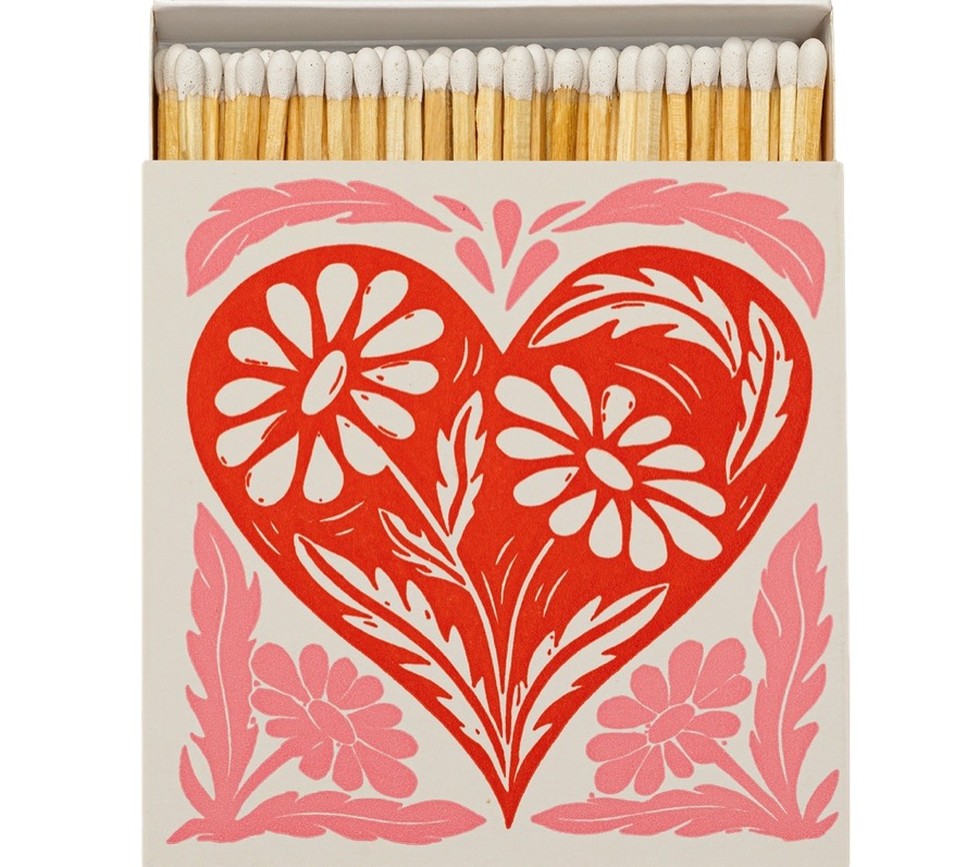 A cream matchbox printed with a red and pink folk-art heart made of daisies